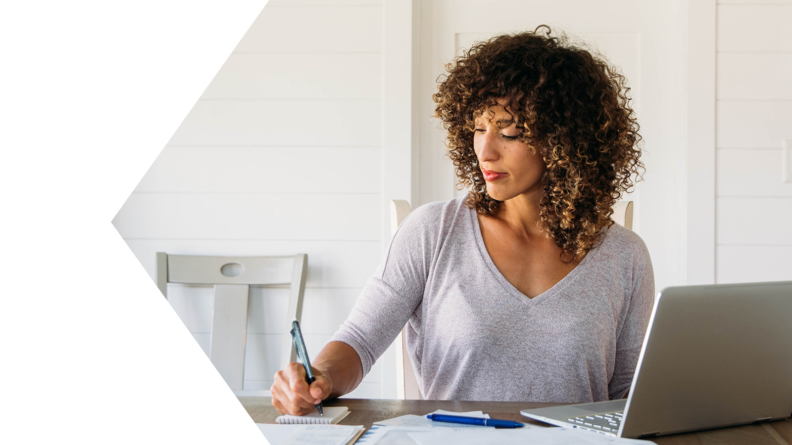 Woman taking notes next to laptop